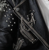 Unisex silver safety pin brooch with chains and crosses, styled on a black studded leather jacket. Perfect for edgy looks.