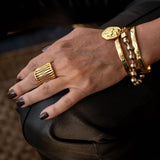 Chic gold bracelet with ball chain and Greek coin, featuring a 24K gold-plated design, shown worn on a model's wrist.
