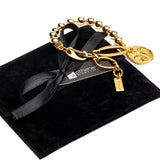 Chic gold bracelet with a ball chain design featuring a Greek coin, presented on a black suede pouch with a ribbon.