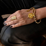 Chic gold bracelet with ball chain and Greek coin, featuring a textured coin charm and shiny ball chain, worn on a hand.