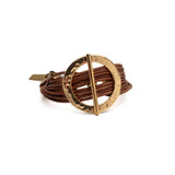 Chunky bracelet featuring a hammered gold metal hoop and bar, accented with multiple natural brown leather strands.