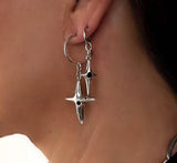Silver hoop earrings with dangle cross and black enamel charms, showcasing layered stacking design.