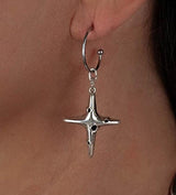 Silver hoop earring featuring a dangle cross pendant with black enamel accents, worn on an earlobe.
