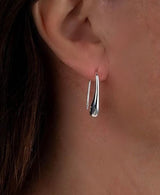 High-polished silver teardrop earrings, approximately 2 inches long, elegantly hanging from an ear lobe.