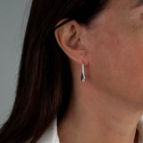 High polished silver teardrop earrings hanging from a model's ear, measuring approximately 2 inches in length.