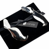 Sculptural silver twisted earrings on a black pouch, showcasing a fluid, modern design with bold curves.