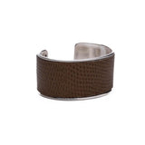 Wide brass bangle featuring beige-toned animal print leather inlay, with a smooth, textured finish.