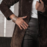 Wide brass bangle featuring beige-toned animal print leather on a textured band, worn on a model's wrist.