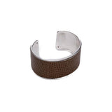 Wide brass bangle featuring beige animal print leather inlay and open-cuff design for adjustable fit.