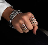 Adjustable stainless steel ring with two irregular funky bars, worn on fingers alongside a silver bracelet.