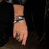 Multi-strand hematite wrap bracelet with polished beads and silver-tone accents, layered on a wrist with a bold ring.