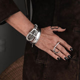 Multi-strand silver chain bracelet featuring a chunky buckle clasp, worn on a hand with dark nail polish.