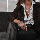 Chunky chain bracelet with vintage coins and leather closure; silver-plated links and intricate coin charms, worn on wrist.