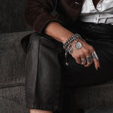 Chunky silver-plated chain bracelet with vintage coins and leather closure, worn on a model's wrist.