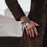 Chunky silver-plated chain bracelet featuring vintage-inspired coins and a leather closure, worn on a model's wrist.