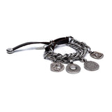 Chunky silver-plated bracelet featuring vintage coin charms and a dark leather closure, creating a bold, bohemian style.