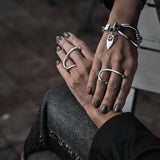 Adjustable two-finger ring in irregular geometric shapes, plated in sterling silver, worn with elegant fingers and a bracelet.
