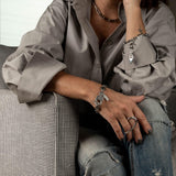 Two-finger adjustable ring in irregular sterling silver, worn on a model's hand with casual attire and accessories.