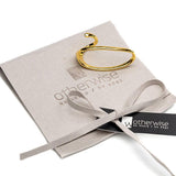 Gold plated adjustable two-finger ring with a unique geometric design, resting on a light gray suede pouch.