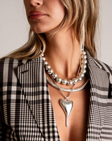 Chunky silver ball chain choker worn under a layered silver necklace, styled with a checkered blazer.