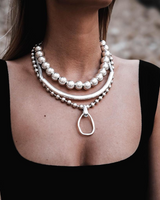 Chunky silver ball chain choker layered with a sleek curved metal piece, worn above a black top.