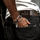 Edgy metal and leather bracelet featuring irregular silver design, worn on wrist with black denim. Adjustable fit with extension chain.