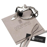 Adjustable black leather and irregular silver-plated metal bracelet with a unique charm, presented on a suede pouch.