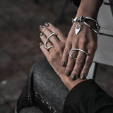Statement bracelet featuring an irregular silver design paired with black leather, worn on a model’s wrist alongside chunky silver rings.