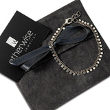 Antique plated silver anklet with round charms, displayed on a velvety pouch with a blue ribbon.