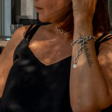 Stainless steel thick chain anklet worn as a bracelet, featuring oval links with a charm, styled with a black top.