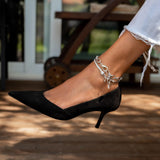 Stainless steel anklet featuring thick oval links, worn on the ankle, paired with a pointed-toe black heel.