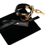 Chunky double link bracelet featuring black leather straps and honey gold stainless steel links, presented on a suede pouch.