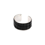 Wide brass cuff bracelet featuring embossed black leather with a textured animal print, adjustable for a custom fit.
