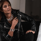 Woman wearing a black leather jacket with studded details and silver jewelry.