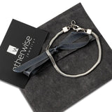 Silver snake chain anklet displayed on a gray suede pouch, featuring a clasp and a decorative ribbon tie.