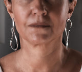 Large asymmetric dangle earrings with irregular wire dangles and hammered stud tops, worn by a model.