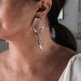 Large asymmetric dangle earrings with hammered studs, featuring flowing, irregular metal wire dangles.