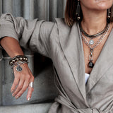 Bronze Hematite Bracelet featuring a dense metallic finish, worn stacked with other bracelets, adjustable slider closure.
