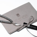 Edgy chic bracelet featuring silver hematite beads and a sterling silver tooth charm, presented in a suede pouch.