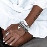 Silver hematite bracelet with tooth stack detail, worn stacked with multiple bracelets on a wrist.