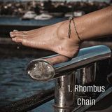 Silver rhombus chain anklet worn on the ankle, showcasing a delicate design against a beach backdrop.