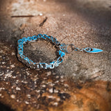 Stainless-steel anklet featuring intricate square Byzantine links with a turquoise accent and an ornate silver pendant.