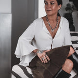 Woman in a white blouse and brown skirt sitting on a zebra-patterned chair.