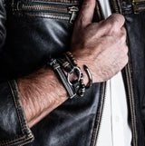 Black leather wrap bracelet with iron chains and metal elements, showcased on a hand wearing a leather jacket.