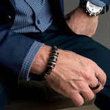 Men’s bracelet features silver-plated and leather accents on dark brown PU leather, worn on a wrist with a watch.