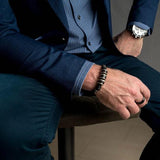 Men's bracelet featuring silver-plated and leather elements on dark brown PU leather, worn on a wrist showing stylish flair.