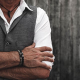 Men's labradorite beaded bracelet features dark beads with iridescent highlights, stacked with other accessories on the wrist.