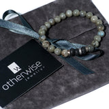Labradorite beaded bracelet featuring semi-precious stones, with a mix of gray and black beads, presented on a suede pouch.