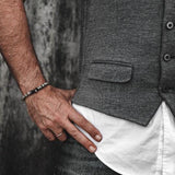 Men's labradorite beaded bracelet featuring iridescent stones, worn casually with a gray vest and white shirt.