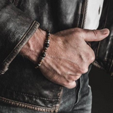 Tiger's eye men's bracelet features beaded design with metal elements, showcased on a wrist wearing a leather jacket.